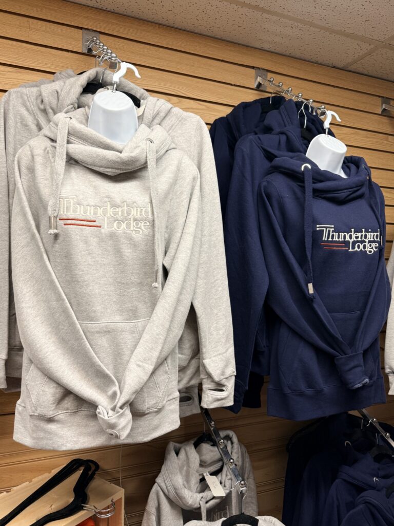 Two hooded sweatshirts hanging on hooks, one light gray and one navy blue